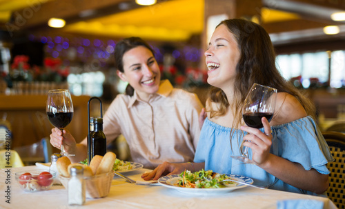 Two positive females dining in restaurant  enjoying meal and conversation