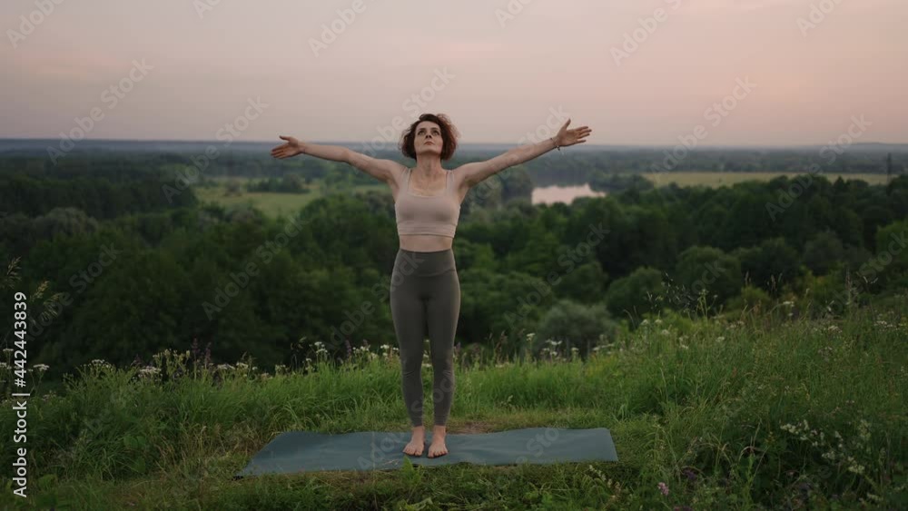 In slow motion, a young woman performs yoga exercises by performing balancing and stretching on top. Calm and peaceful balance of body and soul. Body bends and bends In slow motion, a young woman performs yoga exercises by performing balancing and stretching on top. Calm and peaceful balance of body and soul. Body bends and bends