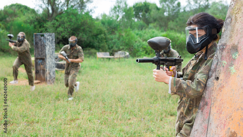 Fototapeta premium Group of friends paintball players of opposite teams in shootout in forest outdoors