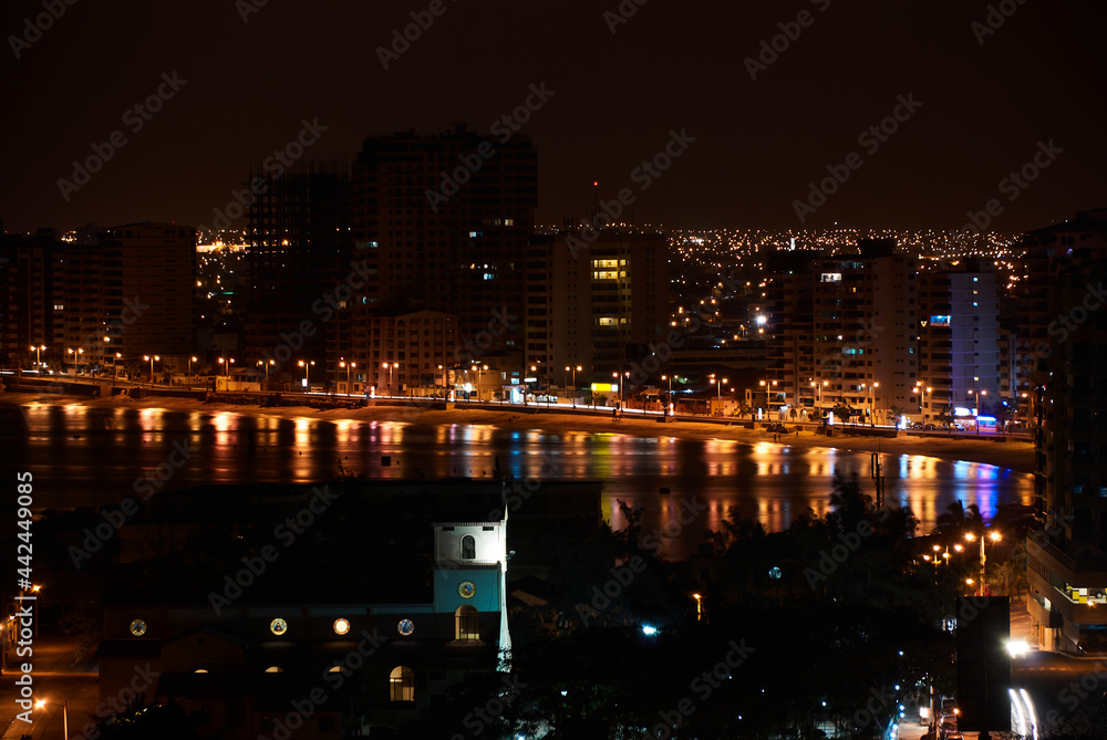 Panoramic night photography of the beach, buildings and houses in the coastal city.