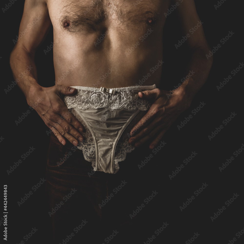 Young naked man with transvestic disorder trying on woman's panties Stock  Photo