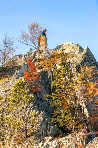 mature tourist posing on the rocks of the mountain round hill on the Alabiya ridge in the Ural mountains on an autumn sunny day. photo