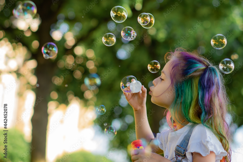 caucasian little girl is blowing a soap bubbles in park. Image with selective focus caucasian little girl is blowing a soap bubbles in park. Image with selective focus