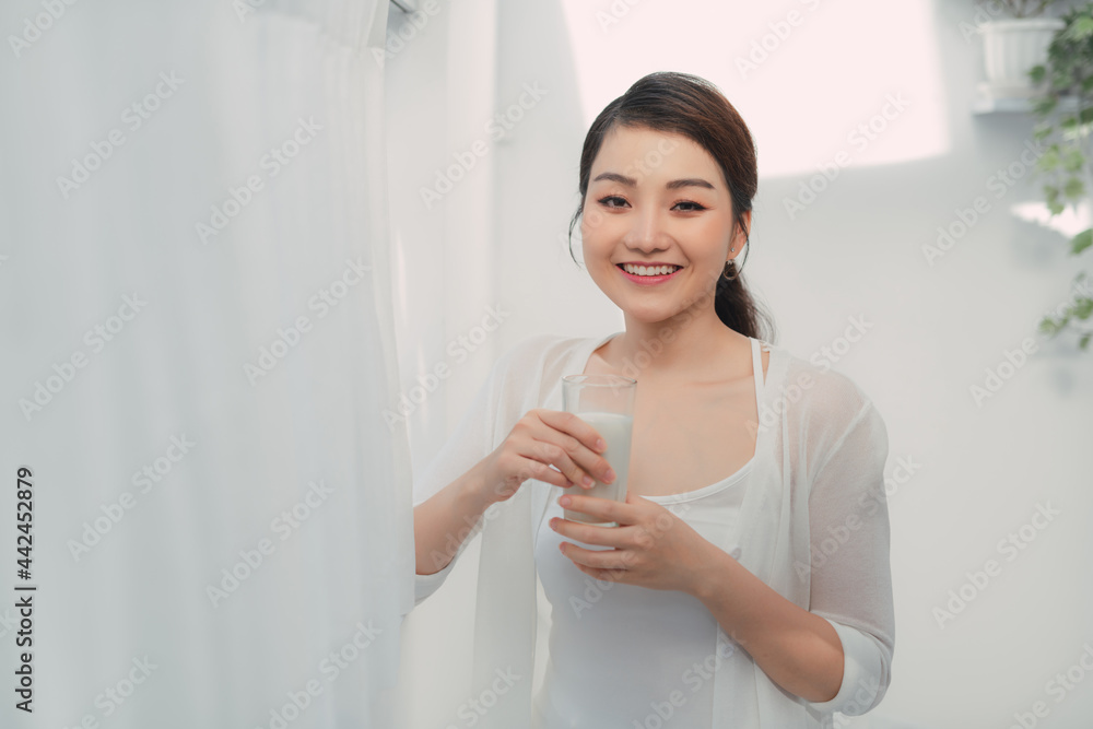 Young asian woman standing beside window and holding mug in bedroom at home, Young asian woman standing beside window and holding mug in bedroom at home,