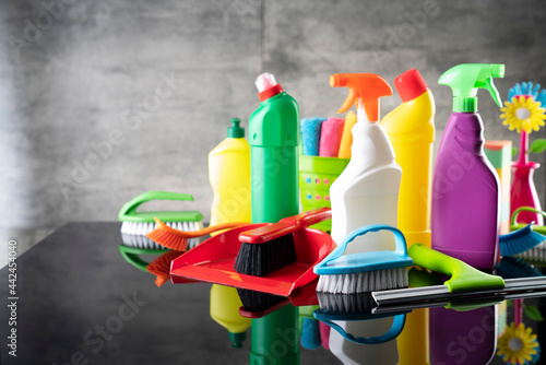 Summer house and office cleaning. Colorful set of bottles with clining liquids and colorful cleaning kit on the gray tiles background.