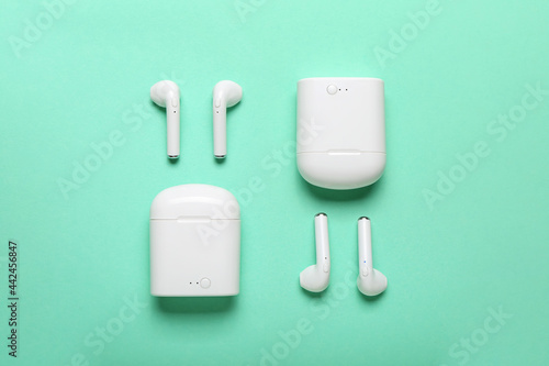 Modern earphones with cases on color background
