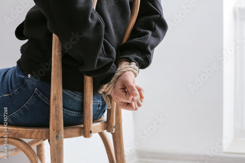 Photography Female hostage with tied hands sitting on chair in room