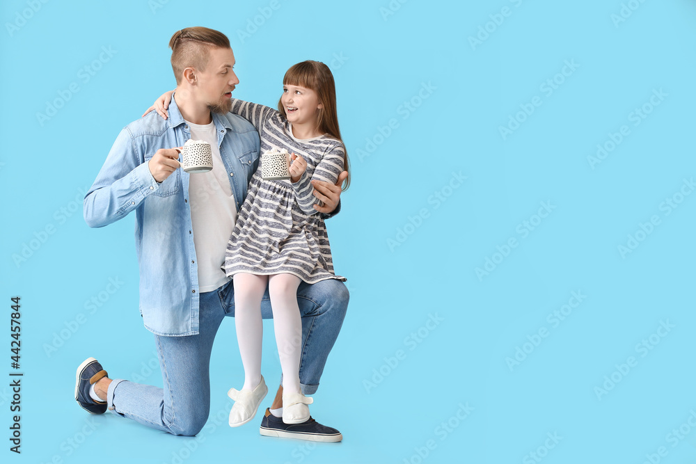 Happy daughter and father with cups of hot cocoa on color background Happy daughter and father with cups of hot cocoa on color background