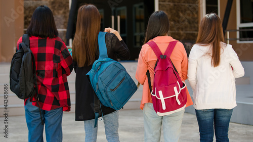 Back view of group of four young attractive asian girls college students walking together in university campus. Concept for education, friendship and college students life