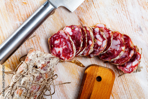 Traditional Italian dry cured pork sausage Salame piacentino with sliced pieces on wooden background photo