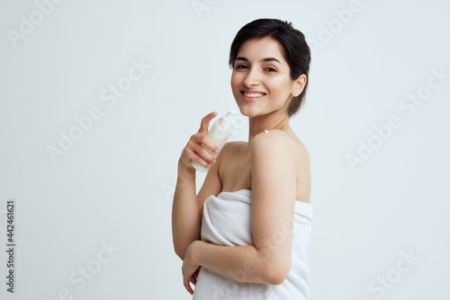brunette in towel with lotion moisturizing clean skin spa treatments