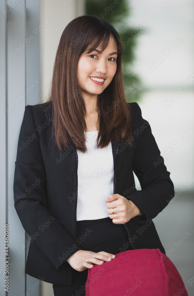Confident businesswoman standing in office corridor and looking at camera Confident businesswoman standing in office corridor and looking at camera