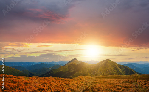 Sunset landscape of high mountain peaks under vibrant colorful evening sky.