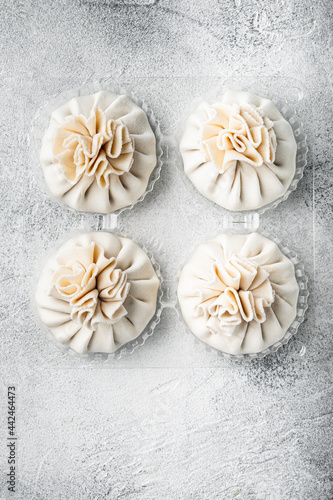 Uncooked Baozi chinese dumplings. Azian dumplings, in plastic tray, on gray stone background, top view flat lay, with copy space for text