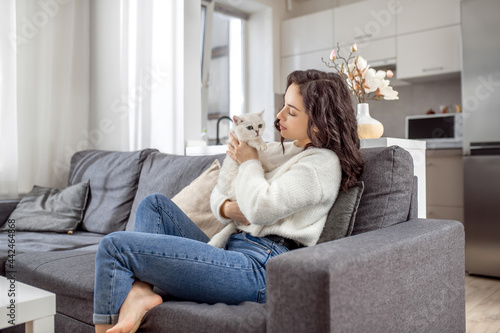 Young woman in white sweater and her cat at home