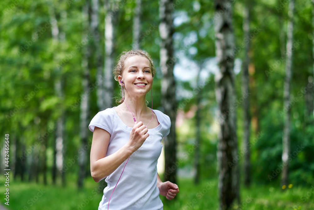 Running woman atletic spotsman trains in the summer park. Outdoor fitness portrait after rain