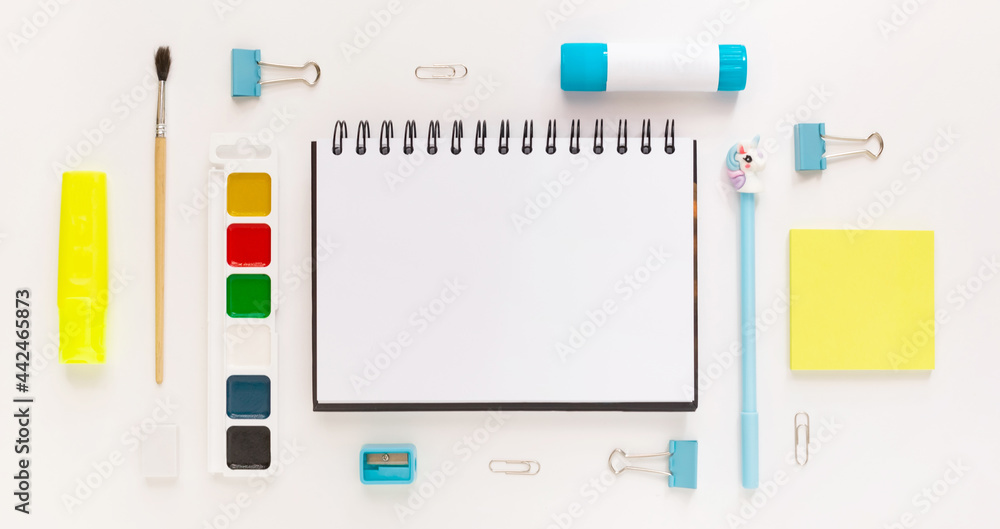 Top view of modern white, blue, yellow office desktop with school supplies and stationery on table around empty space for text. Back to school concept flat lay with mockup Top view of modern white, blue, yellow office desktop with school supplies and stationery on table around empty space for text. Back to school concept flat lay with mockup