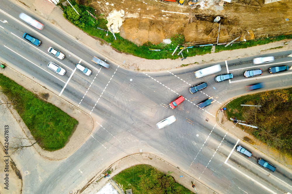 Top down aerial view of busy street intersection with moving cars traffic.