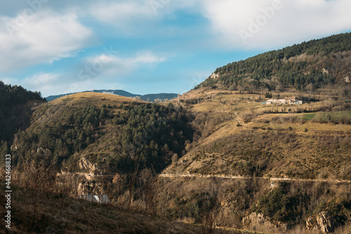 Beautiful rural landscape of mountainous area, few farm houses, blue sky with white clouds on sunny day in winter, countryside scenery in Spain