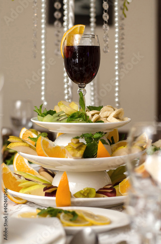 Wallpaper Mural Glass of red wine with a slice of orange on a plate with fruit, bananas, kiwi, pear, apple, orange, lemon on the banquet table Torontodigital.ca