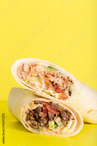 Doner roll shawarma with chicken and vegetables on yellow