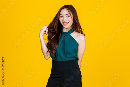 30s cute and charming curly hair Asian female brunette pose to camera with a joyful and positive gesture for advertising use purpose. Taken with studio flash isolated on yellow background