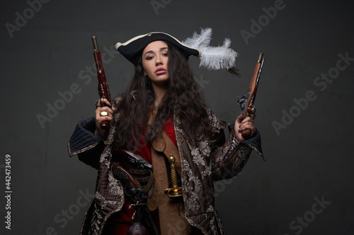 Woman corsair with long wavy hairs and guns