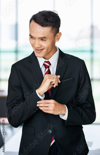 Cheerful Asian businessman standing in workplace