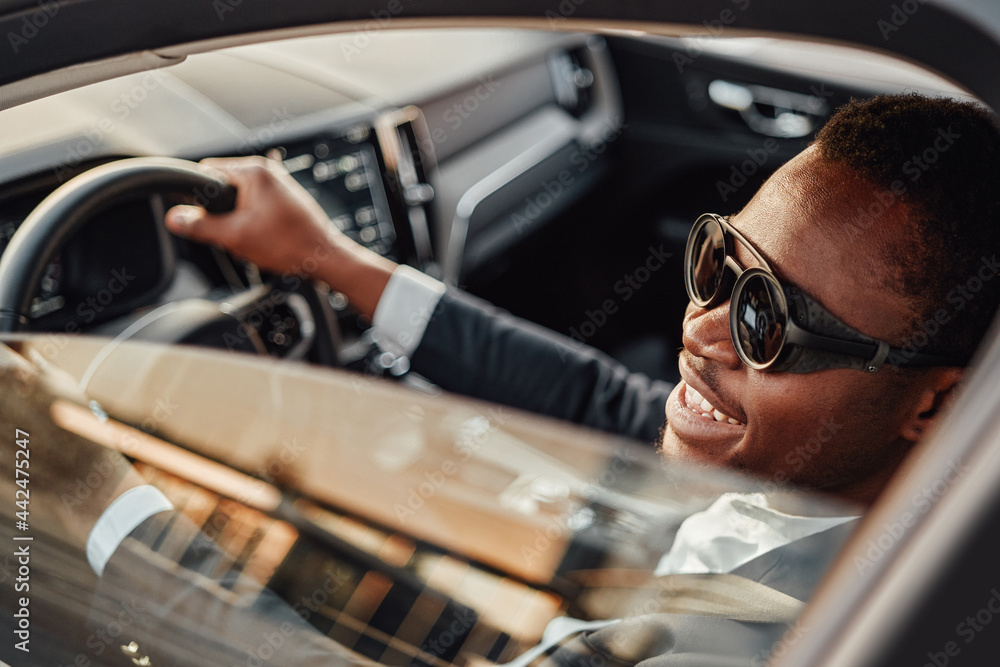 Joyful african american businessman inside of car