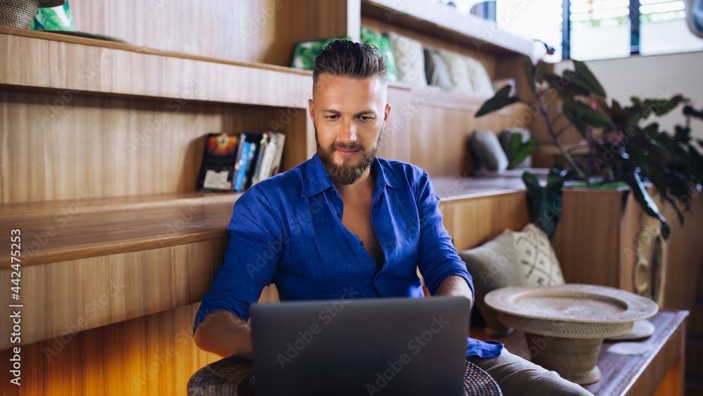 Young European man in blue shirt with laptop in internet cafe