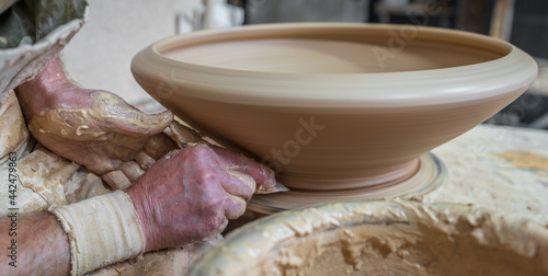 Potter working softly on pot with hand
