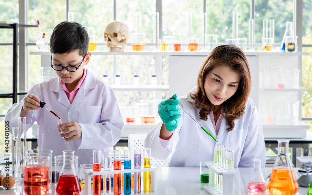 Concentrated Asian college students conducting experiment with colorful liquids during scientific research in laboratory Concentrated Asian college students conducting experiment with colorful liquids during scientific research in laboratory