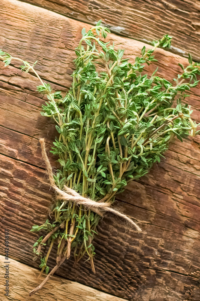 A bunch of thyme on a table made of brown boards. Vertical photo.