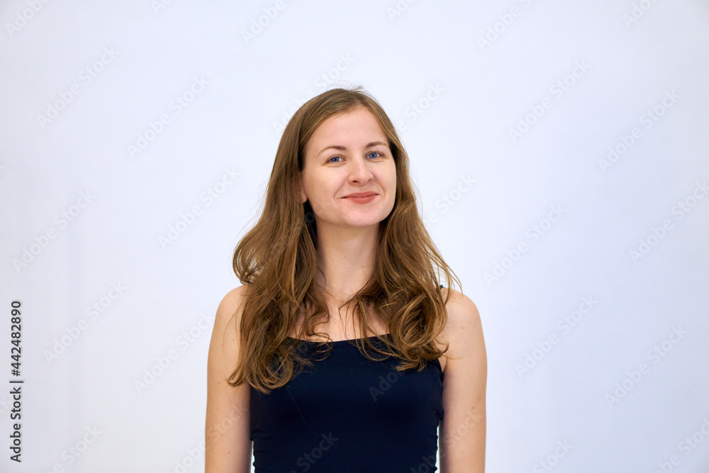 A beautiful Caucasian woman stands on a white background in a blue sweater with loose hair. The woman shows emotions. A beautiful Caucasian woman stands on a white background in a blue sweater with loose hair. The woman shows emotions.