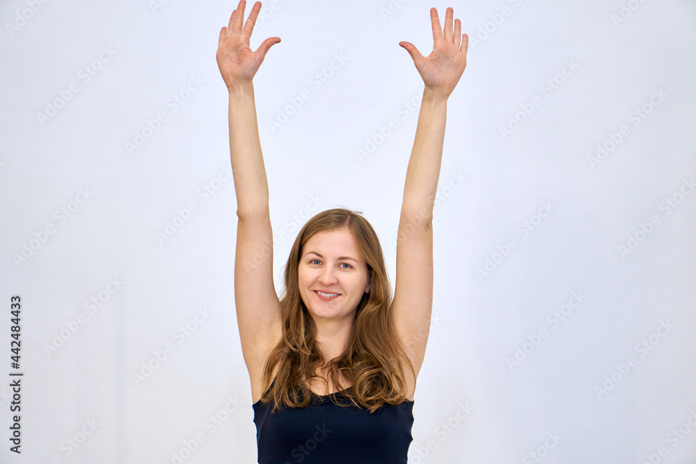 A beautiful Caucasian woman stands on a white background in a blue sweater with loose hair. The woman shows emotions. A beautiful Caucasian woman stands on a white background in a blue sweater with loose hair. The woman shows emotions.