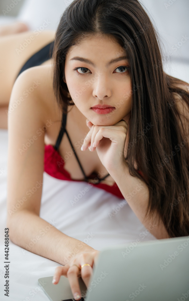 Beautiful young naughty sexy girl with long hair and romantic underwear lie down on bed and attentively consider to type on laptop on rest day, new normal work at home concept. Beautiful young naughty sexy girl with long hair and romantic underwear lie down on bed and attentively consider to type on laptop on rest day, new normal work at home concept.