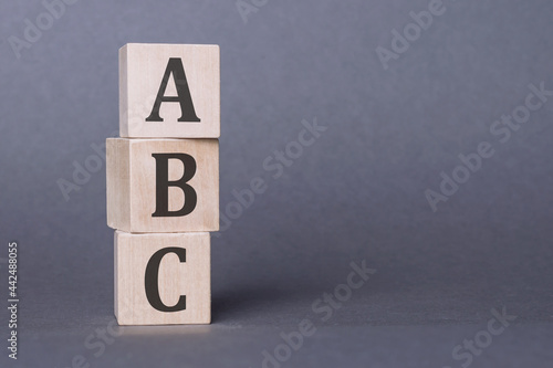 ABC - text, written on wooden blocks, on gray background.