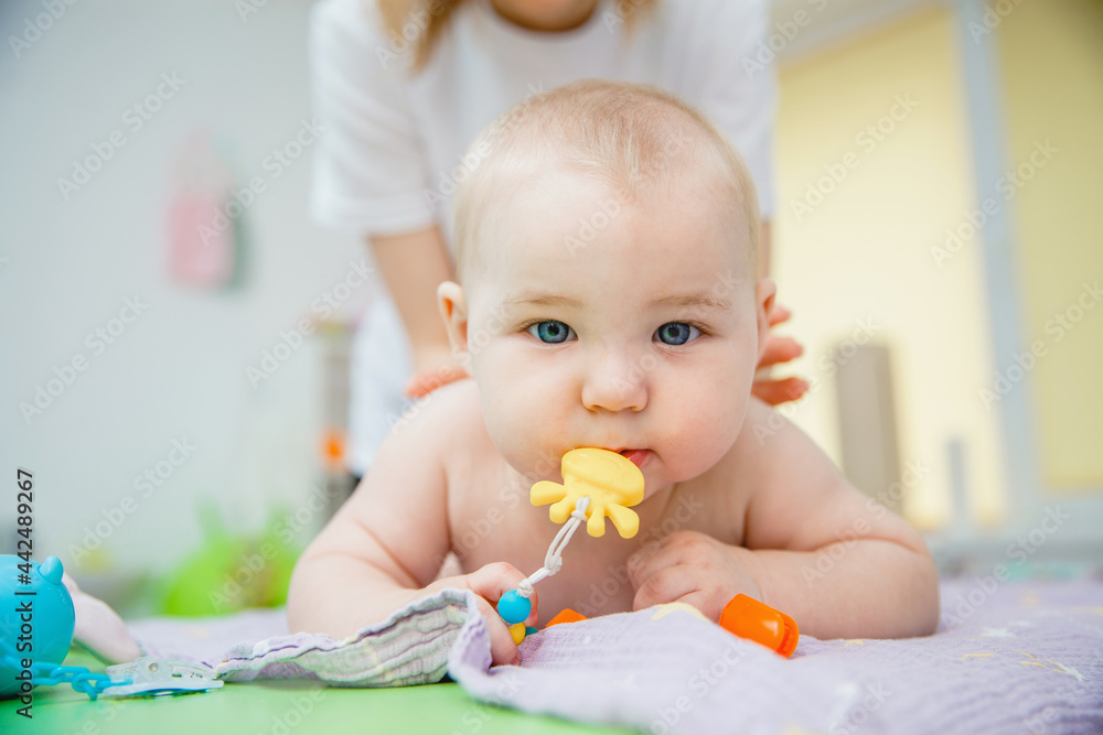 A small child lying on his stomach gets a massage in a massage room. He has a toy in his mouth A small child lying on his stomach gets a massage in a massage room. He has a toy in his mouth