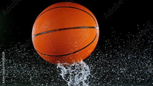 Falling basketball ball on water surface, black background. Top down view. © Lukas Gojda