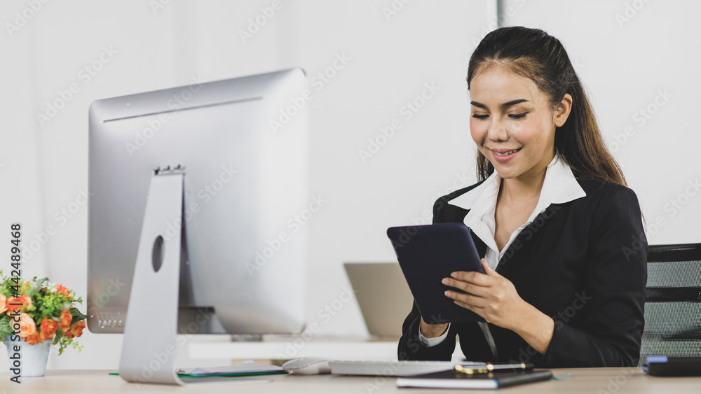 Asian office people are businesswoman wearing black suit using tablet instead computer at work desk look to feel happy with smile on face Asian office people are businesswoman wearing black suit using tablet instead computer at work desk look to feel happy with smile on face