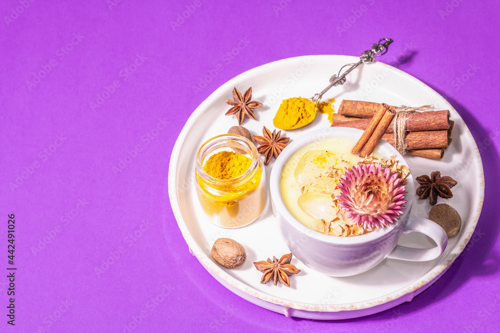 Golden turmeric milk with ice on bright yellow background Golden turmeric milk with ice on bright yellow background