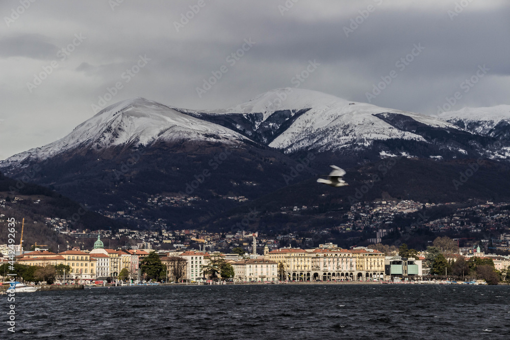 Lugano in winter, Switzerland. Old city of Lugano in front of snowy Alps. Cold winter day.