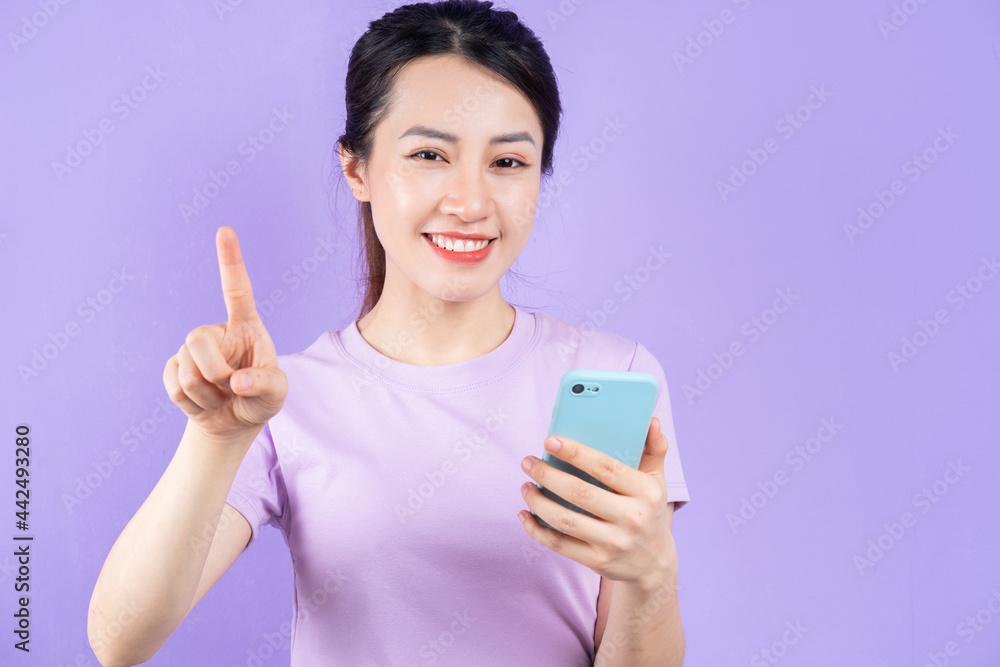 Young Asian woman using smartphone on purple background Young Asian woman using smartphone on purple background