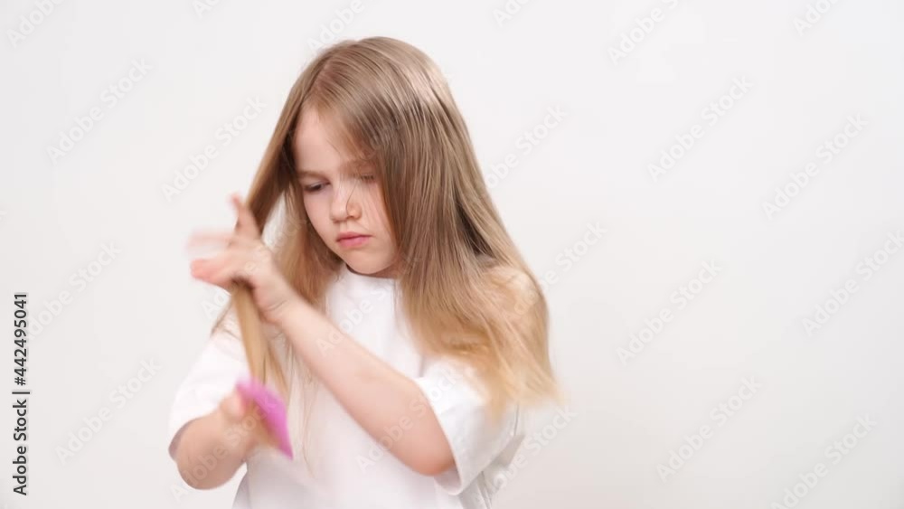 kid girl itself combs long and tangled hair on a white background. cosmetics for the care of children's hair. kid girl itself combs long and tangled hair on a white background. cosmetics for the care of children's hair.