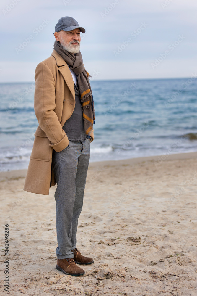 an aged man walking along the beach against the background of the sea