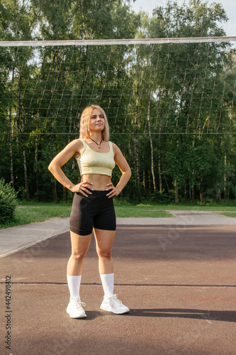 A blonde girl in a sports uniform stands on a volleyball court in summer © Наталья Анюхина