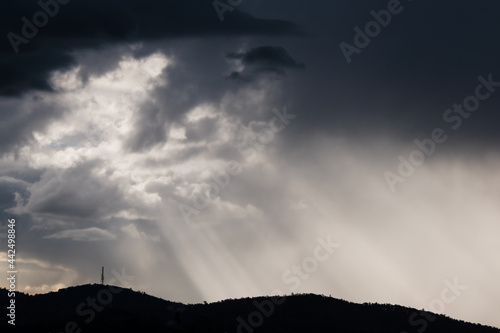 thick stormy clouds over the mountains with intense sun rays peaking through and contrasty light