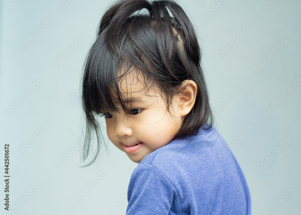 A headshot portrait of a cheerful baby Asian woman, a cute toddler little girl with adorable bangs hair, a child wearing a blue sweater smiling and don't looking to the camera.