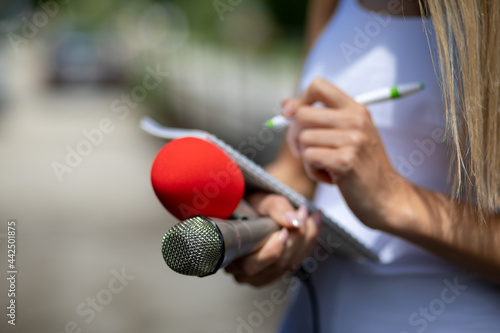 News reporter or TV journalist at press conference, holding microphone and writing notes photo