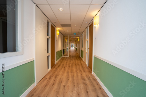 Corridor with doors on both sides. The floor is made of wood and the walls are white